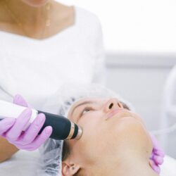 Woman receiving a high-tech laser skincare treatment in a clinical setting.